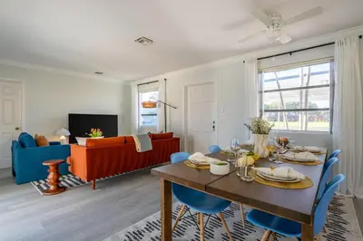 a living room with a table and blue chairs at Tropical Retreat on Sheridan l Near Beach and Parks in Hollywood