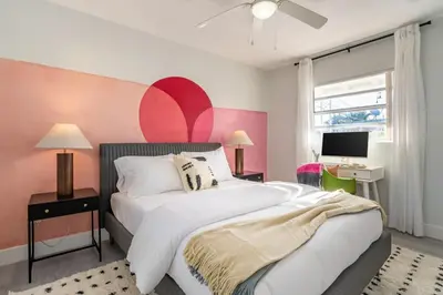 a bedroom with a large bed and a pink wall at Tropical Retreat on Sheridan l Near Beach and Parks in Hollywood