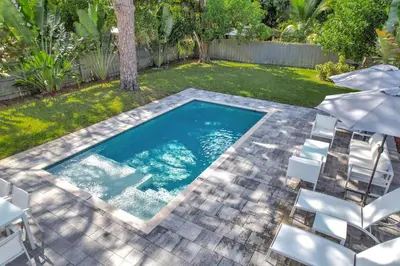 a swimming pool with chairs and a yard at Palm Haven in Fort Lauderdale