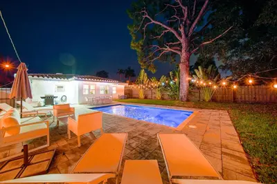 a backyard with a swimming pool at night at Palm Haven in Fort Lauderdale