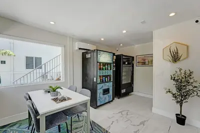 a living room with a white table and a refrigerator at Eden Collection Studio Steps to Beach in Fort Lauderdale