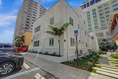 a white building with a palm tree in a parking lot at Eden Collection Studio Steps to Beach in Fort Lauderdale