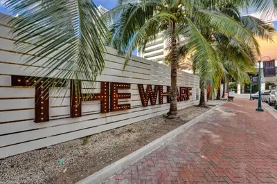 a wall with a sign on it next to palm trees at Eden Collection Studio Steps to Beach in Fort Lauderdale