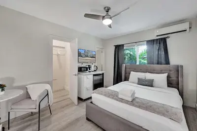 a bedroom with a bed and a table and a kitchen at Eden Collection Studio Steps to Beach in Fort Lauderdale