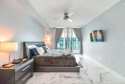 a bedroom with a bed and a desk and a window at Stylish Brickell Penthouse with Exclusive Perks in Miami