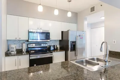 a kitchen with white cabinets and a stainless steel refrigerator at Stylish Brickell Penthouse with Exclusive Perks in Miami