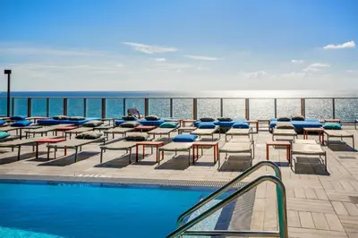 a resort with a pool and chairs and the ocean at Lyfe Resort & Residences By OceanMiami in Hollywood