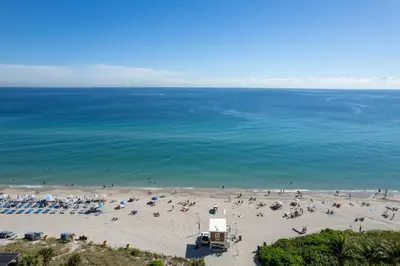 an aerial view of a beach with a lot of people at Coastal Luxe Residences - Premium Suites with Pool and Water Views in Hallandale Beach