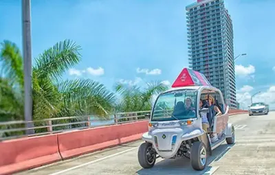 a golf cart driving down a road with a sign on it at Coastal Luxe Residences - Premium Suites with Pool and Water Views in Hallandale Beach