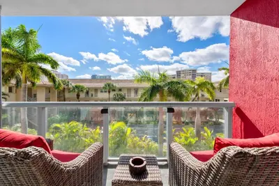 a balcony with chairs and a view of a building at Coastal Luxe Residences - Premium Suites with Pool and Water Views in Hallandale Beach