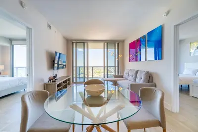 a living room with a glass table and chairs at Coastal Luxe Residences - Premium Suites with Pool and Water Views in Hallandale Beach