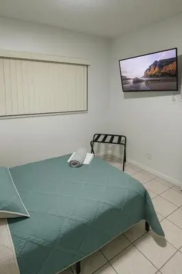 a bedroom with a green bed and a chair at Santamaria Fort Lauderdale Airport in Fort Lauderdale