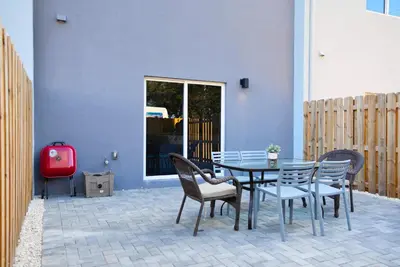 a patio with a table and chairs and a red suitcase at Family-Friendly Townhouse Getaway Near Top Attractions in Golden Glades