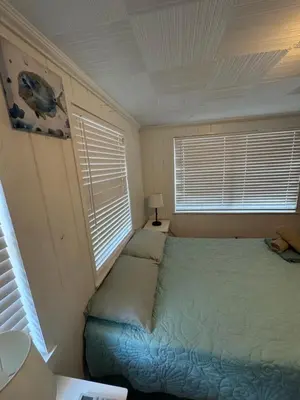 a small bedroom with a bed and two windows at La Mare Fort Lauderdale Airport in Fort Lauderdale