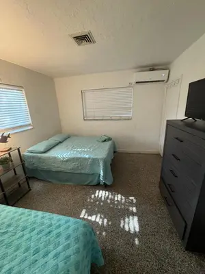a bedroom with two beds and a dresser and a television at La Mare Fort Lauderdale Airport in Fort Lauderdale