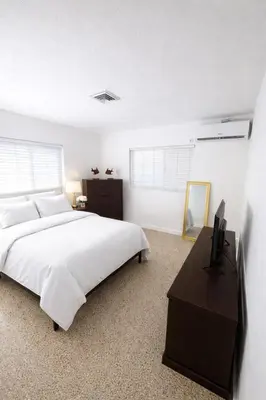 a white bedroom with a bed and a television at La Mare Fort Lauderdale Airport in Fort Lauderdale