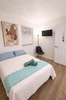 a bedroom with a bed and a chair and a television at La Mare Fort Lauderdale Airport in Fort Lauderdale