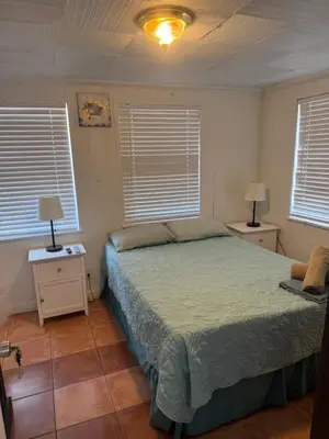 a bedroom with a bed and two night stands and two windows at La Mare Fort Lauderdale Airport in Fort Lauderdale