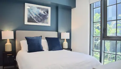 a bedroom with a bed with blue walls and windows at The Juliet VI Vibe 8701 in Miami