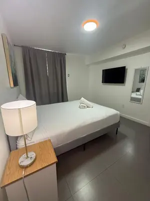 a bedroom with a bed with a lamp and a tv at Wynwood Bungalows By Renzzi in Miami