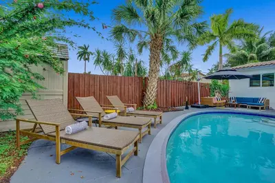 a pool with chairs and a fence with palm trees at Newly Renovated w Heated Saltwater Pool & Hot Tub in Hollywood