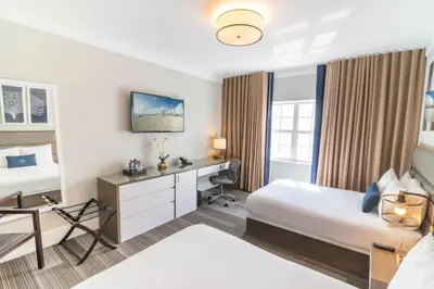 a hotel room with two beds and a desk at San Juan Hotel Miami Beach in Miami Beach