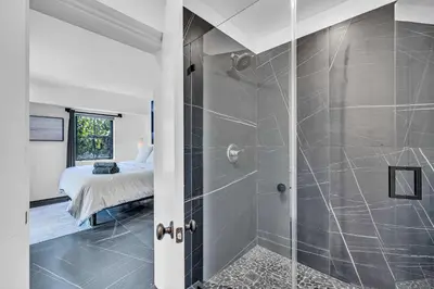 a bathroom with a walk in shower next to a bed at Family Vacation Home in Miami