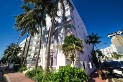 a tall white building with palm trees in front of it at Le Particulier Miami in Miami Beach