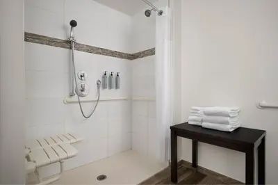 a bathroom with a shower and a table with towels at Residence Inn by Marriott Miami Beach Surfside in Miami Beach