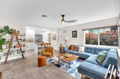 a living room with a blue couch and a table at The Frolics -Stunning Wilton Manors Pool Home in Fort Lauderdale
