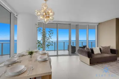 a living room with a table and a chandelier at Beachfront Balcony Apartment Amenities in Hollywood