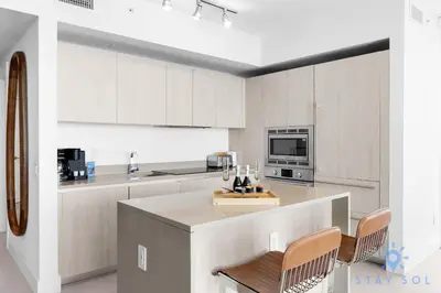 a kitchen with white cabinets and a counter with chairs at Beachfront Balcony Apartment Amenities in Hollywood