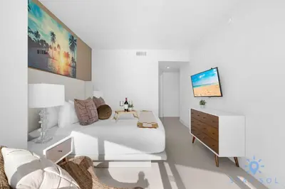 a white room with a bed and a dresser at Beachfront Balcony Apartment Amenities in Hollywood