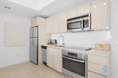 a white kitchen with a microwave and a refrigerator at Stylish -2BR Apartment -Balcony & Pool in Hallandale Beach