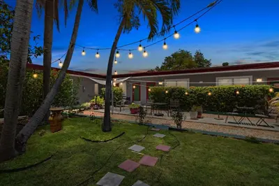 a backyard with string lights and palm trees at Bright 2BR Getaway | BBQ, Garden & Parking in Hollywood