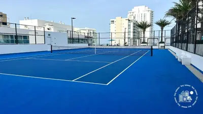 a tennis court with palm trees and buildings in the background at 3 BDR Beach Bliss in Hollywood