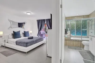 a bedroom with a large bed and a bathroom at Central Stunning Villa with Heated Pool Cabana in Hollywood Ridge Farms