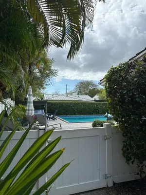 a white fence next to a swimming pool at Charming two Bedroom in the Gables For Rent in Miami