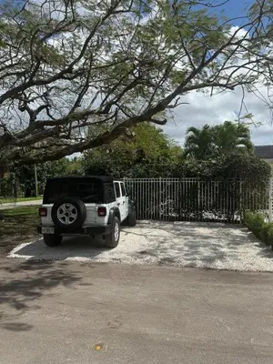 a white jeep parked in front of a fence at Charming two Bedroom in the Gables For Rent in Miami