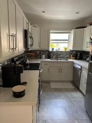 a white kitchen with white cabinets and a window at Charming two Bedroom in the Gables For Rent in Miami