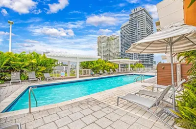 a swimming pool with chairs and an umbrella at Midblock Midtown Miami 1B W Spa Pool Gym in Miami