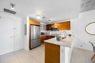 a kitchen with wooden cabinets and a stainless steel refrigerator at Midblock Midtown Miami 1B W Spa Pool Gym in Miami