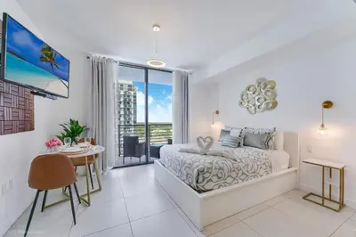 a bedroom with a bed and a desk and a window at Stylish Studio with Pool View at the Heart of Downtown Doral in Miami