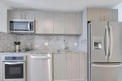 a kitchen with stainless steel appliances and wooden cabinets at Stylish Studio with Pool View at the Heart of Downtown Doral in Miami