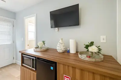 a tv on top of a wooden cabinet with flowers on it at Dania Beach 1BR | Steps to Ocean + Parking in Dania Beach