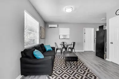 a living room with a black couch and a table at Triplex with 3 Bedrooms, 6 Min/Beach+Free Parking in Dania Beach