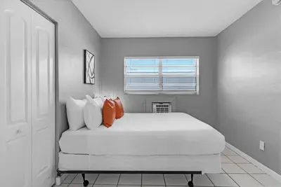 a bedroom with a large white bed with two orange pillows at Cozy 1BR Retreat | 6-Min to Beach + Free Parking in Dania Beach