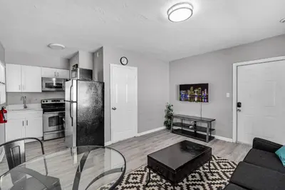 a kitchen and a living room with a glass table at Chic 1BR Getaway Near FLL Airport + 6 MN to Ocean in Dania Beach