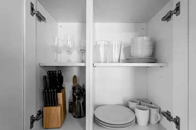 a white pantry with plates and glasses on shelves at Chic 1BR Getaway Near FLL Airport + 6 MN to Ocean in Dania Beach