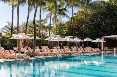 a pool with chairs and umbrellas and palm trees at W South Beach 1B Residence Ocean View in Miami Beach